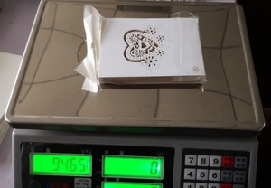 Stack of white laser-cut heart cards on a digital scale showing product weight details