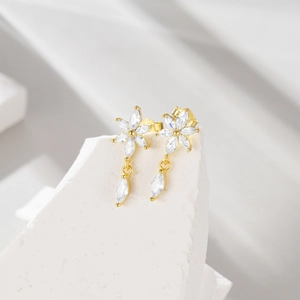 Detailed macro view of S925 sterling silver flower earrings with zircons on white marble