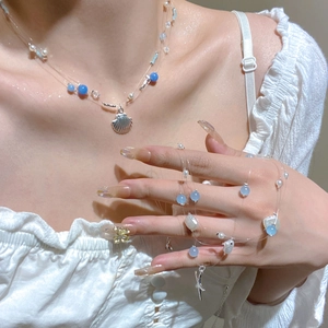 Détail d'un collier bohème multicouche avec pendentif coquillage argenté et perles