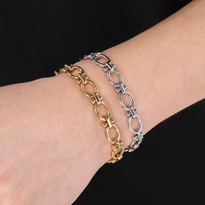 Close-up of chunky gold and silver Cuban chain bracelets with ball accents on wrist