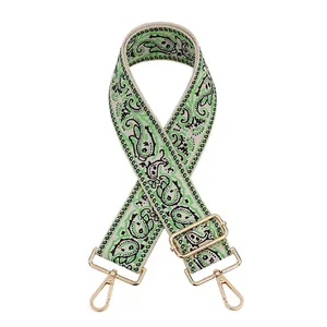 Close-up of adjustable woven bag strap with paisley pattern and golden metal buckles