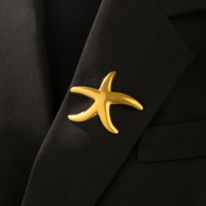 Detail of high-polish gold starfish lapel pin on a black textured suit blazer collar