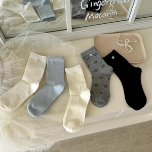 Détails de nœuds tricotés et boutons sur cinq paires de chaussettes en coton pastel