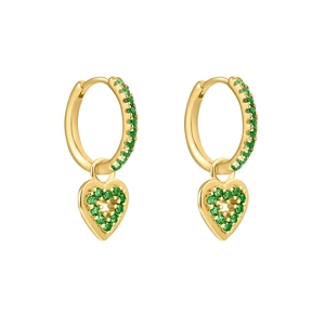 Détail de boucles d'oreilles cœur dorées serties de zircons verts sur fond blanc