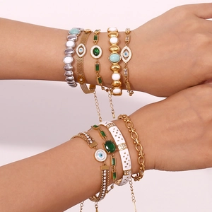 Detail of 18K gold-plated Evil Eye bracelets and layered stone bangles on a wrist