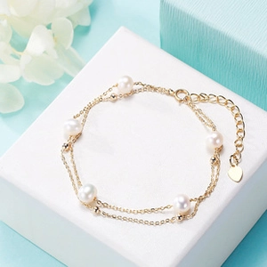Detail of adjustable gold pearl bracelet with heart charm on elegant gift box