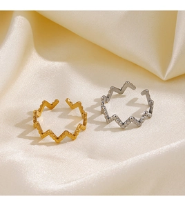 Detailed view of irregular geometric gold and silver open rings on beige satin fabric