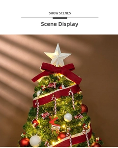 Detail of Christmas tree decorated with glowing white star topper and red velvet ribbons