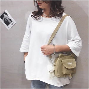 Detail of khaki bear-ear canvas crossbody bag with plush charm on a female model