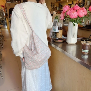 Floral canvas tote bag with wide shoulder strap shown in a lifestyle cafe setting