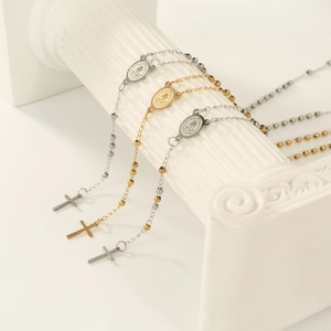 Detail of religious beaded bracelets with medals and crosses on white column pedestals