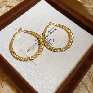 Close-up of golden hoop earrings with twisted texture in a vintage jewelry box