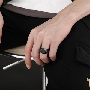 Close-up of a men's black geometric faceted titanium ring shown on a hand model
