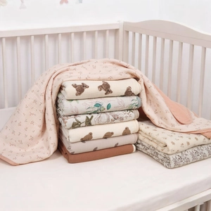 Detailed stack of soft multi-patterned cotton baby blankets in a nursery wooden crib