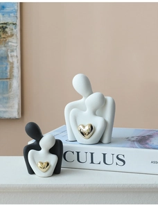 Detailed view of matte ceramic couple figures with gold heart accents on a white book