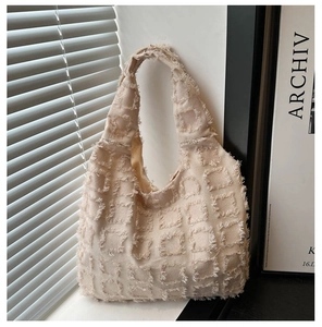 Detail of beige tote bag featuring 3D fringed checkerboard texture and woven fabric