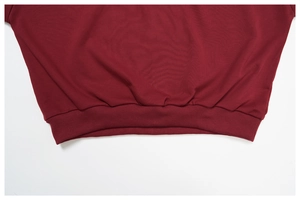 Close-up of ribbed hem detail on premium burgundy cotton sweatshirt with clean stitching