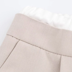 Detailed close-up of apricot wide-leg pants featuring a white elastic waistband and fine stitching