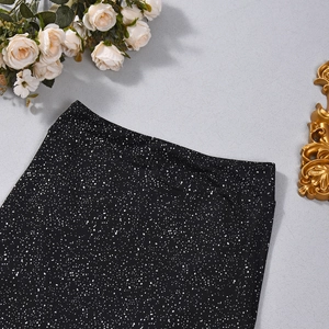 Close-up of high-waisted black skirt featuring white splattered print and elastic fabric