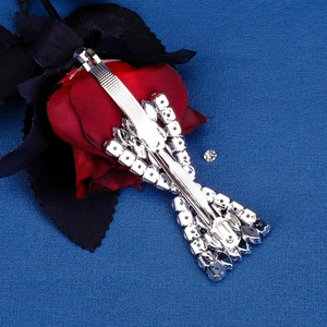 Close-up of silver metal hair clip with sparkling rhinestones on blue textured surface
