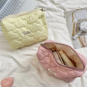Detailed view of quilted cloud texture makeup bags in yellow and pink nylon