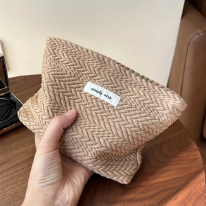 Detail of khaki woven cosmetic bag with zigzag texture and simple wish label