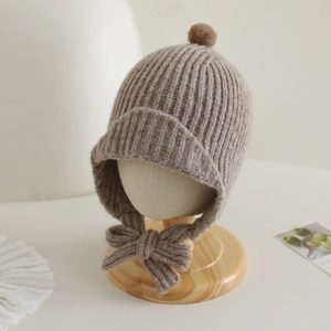 Détail du bonnet d'hiver en tricot kaki avec pompon et nœud décoratif pour bébé