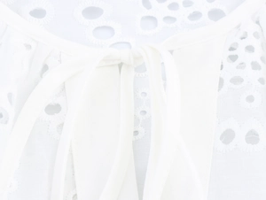Detailed close-up of white lantern sleeve top featuring hollow lace embroidery and neck ties