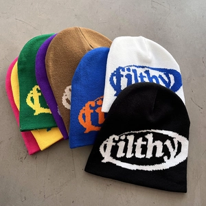 Flat lay of colorful knit beanies with jacquard lettering in multiple vibrant shades