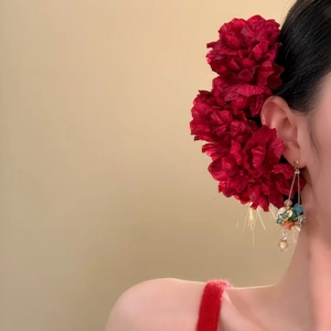 Detail view of elegant red fabric flower hairpins with beaded tassels on model