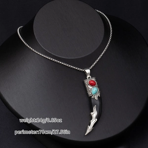 Men's vintage wolf fang necklace detail with red and turquoise gems on a silver chain