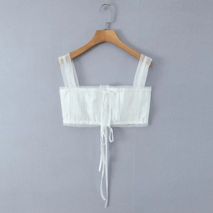 Detailed view of white camisole top with lace straps, ruched fabric, and tie-up front
