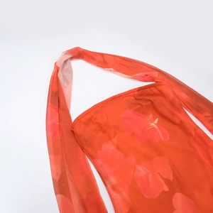 Détail du tissu en maille orange à fleurs montrant le col licou et la texture fluide