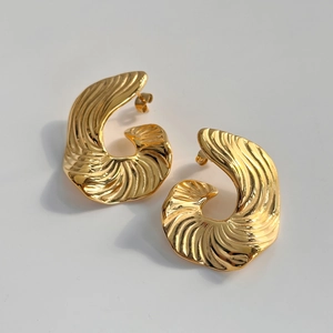 Détails macro de boucles d'oreilles dorées en forme de coquillage à texture nervurée