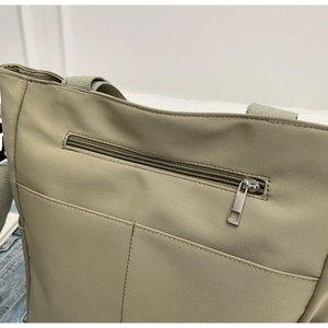 Detail view of khaki canvas tote bag featuring a secure back zipper pocket and stitching