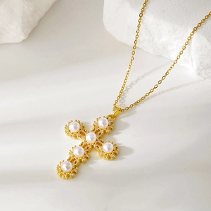 Detail of gold cross pendant with white pearls and shimmering zircons on stone background