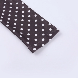 Close-up of long sleeve cuff with white polka dots on black fabric and double-stitched hem