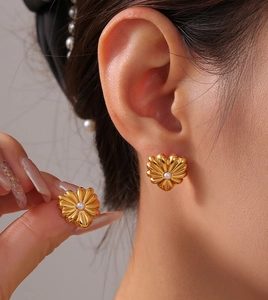Nahaufnahme eleganter goldener Herzohrringe mit Perleneinlage an einem Model