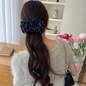 Rear view of a black polka dot bow hair clip on long wavy hair in a cozy setting