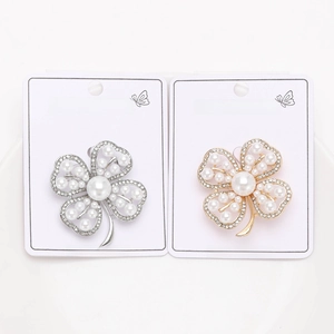 Detailed view of silver and gold alloy four-leaf clover pins with pearls and rhinestones