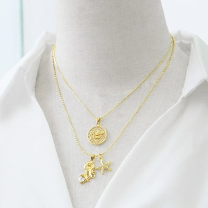 Double-layered gold necklace with mermaid, starfish pendants and circular embossed tag