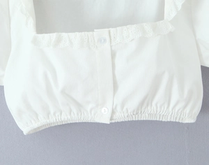 Detail of white lace square neck top showing textured cotton and button closure
