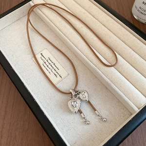 Detail of silver double heart pendants on brown braided rope over jewelry tray