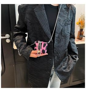 Close-up of pink leopard print mini chain bag paired with a black pleated blazer