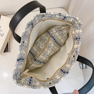 Detail view of cotton tote bag interior with floral zip pocket and leather handles