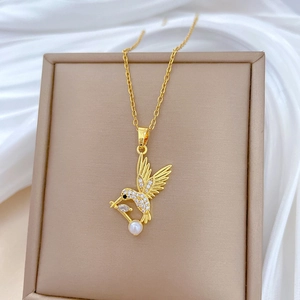 Collier colibri doré de luxe avec diamants blancs et perle sur une boîte à bijoux en velours
