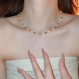 Détail du collier de perles colorées et perle blanche sur cou avec fond doux