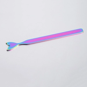 Detailed macro view of iridescent mermaid tail metal makeup mixing stick on grey surface