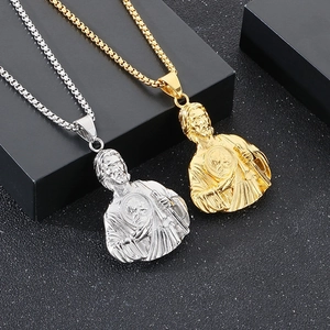 Macro shot of silver and gold St. Jude religious pendants on a textured black surface