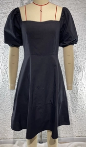 Detail view of a black square neck dress with puff sleeves on a professional mannequin